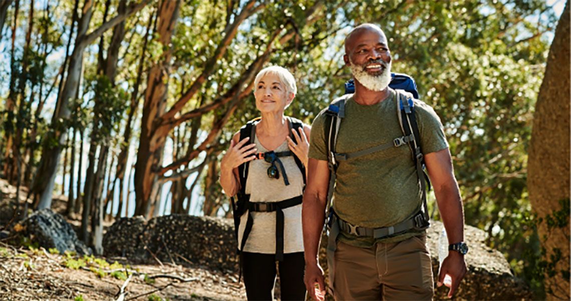 Elder couple hiking through the woods, smiling