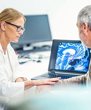 Doctor talking to a patient in front of a monitor with picture of a brain