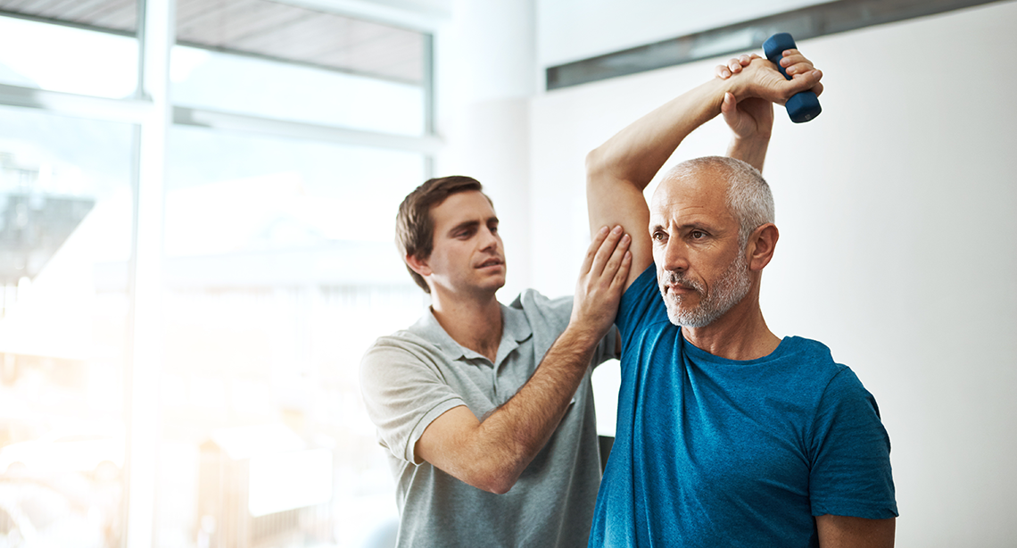 Physical therapist helping a patient lift a dumbbell over their head