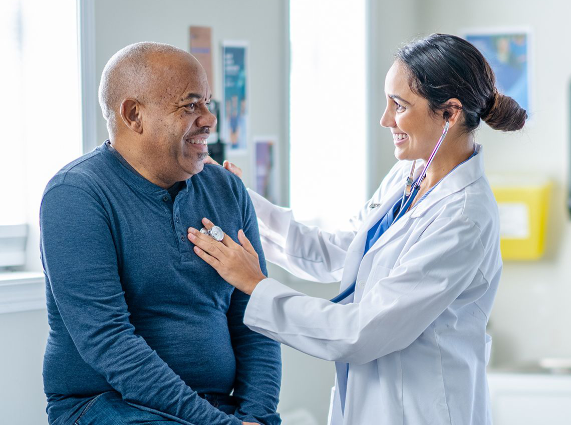 doctor checking patient's heartbeat and they are smiling