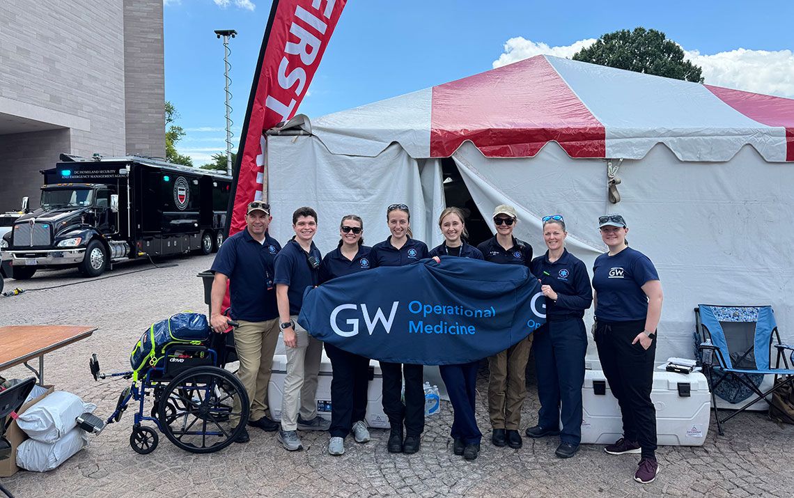 GW Operational Medicine team holding a banner outside of a medical tent
