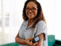 woman with glasses on holding a blood sugar monitor