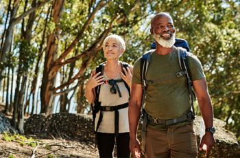 Elder couple hiking through the woods, smiling