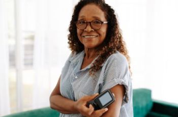 woman with glasses on holding a blood sugar monitor